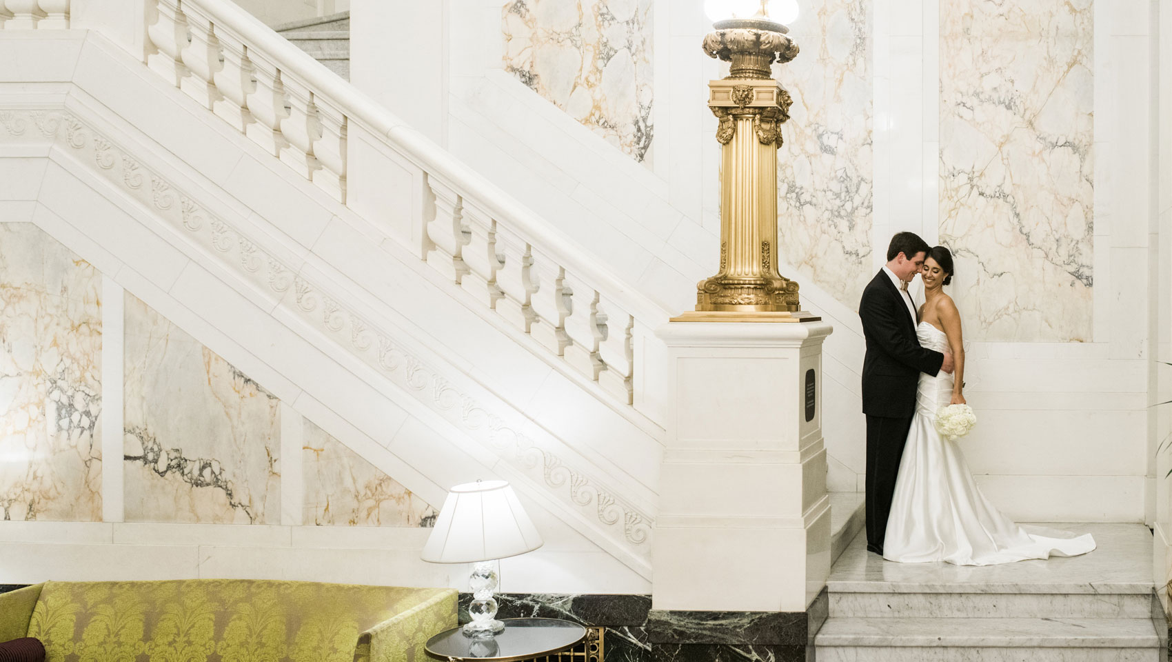 Courtney & Steve pose for a wedding portrait at the foot of the grand marble staircase at Kimpton Hotel Monaco Baltimore.